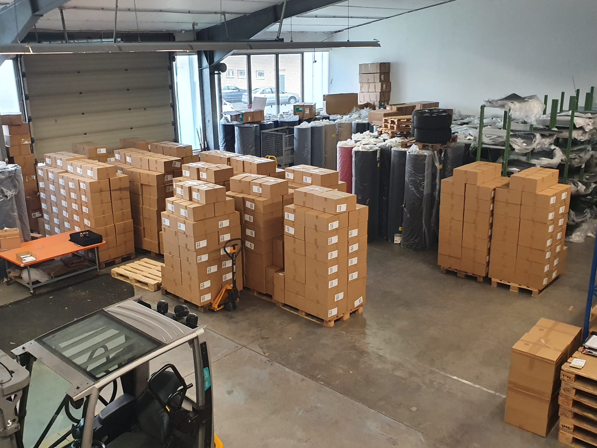 Hunderte fertige Pakette, Teppichrollen und ein Stapler im Lager von Autoteppich-Stylers.